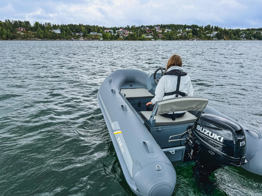 Vrouw bestuurt een grijze RIB boot met Suzuki DF15 buitenboordmotor